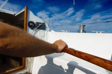 Olgun bir adamın ellerinin geminin korkuluklarına yakın plan çekimi.