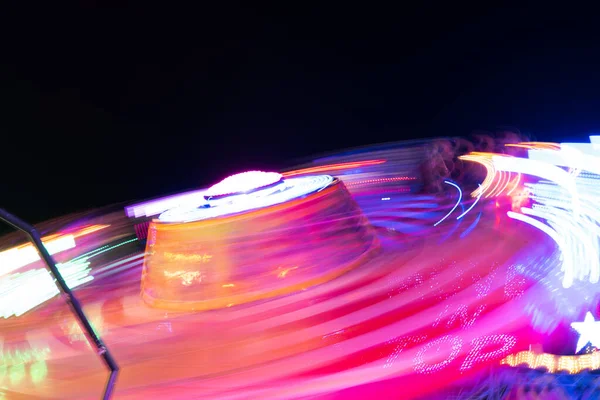 Blurred view of roller coaster at amusement park during night