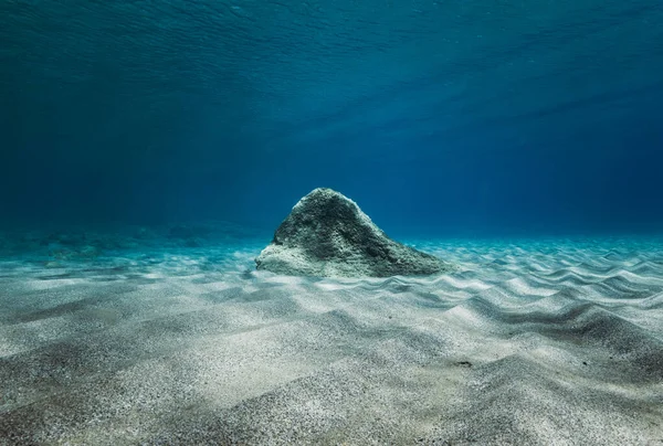 View of underwater stone with rippled sand