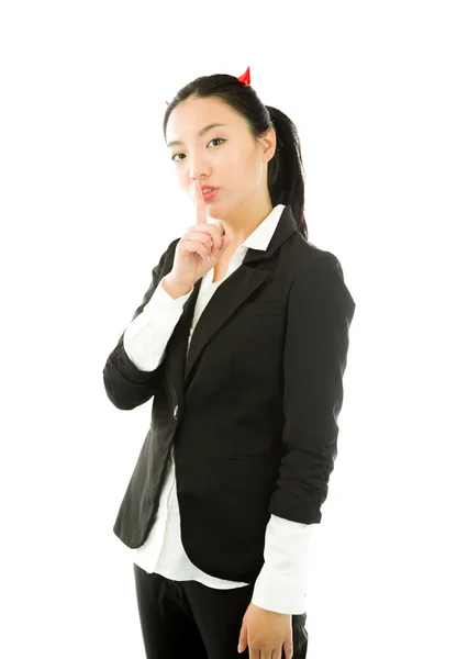 Devil side of a young Asian businesswoman standing with finger on lips asking for silence isolated on white background — Stock Photo, Image