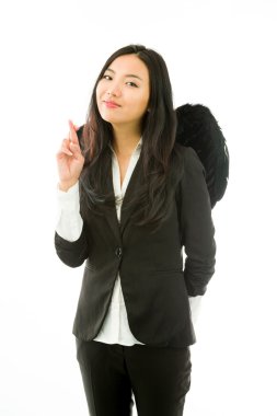 Asian young businesswoman dressed up as black angel with her fingers crossed looking at camera isolated on white background