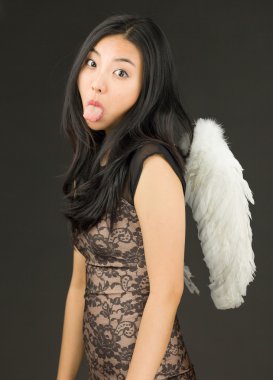 Dilini dışarı çıkaran bir melek gibi giyinmiş Asyalı genç bir kadın.