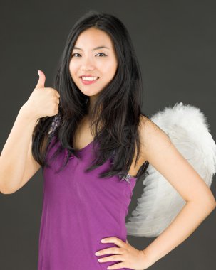 Melek yan işareti Yaşasın gösterilen ve gülümseyen genç bir Asyalı kadın