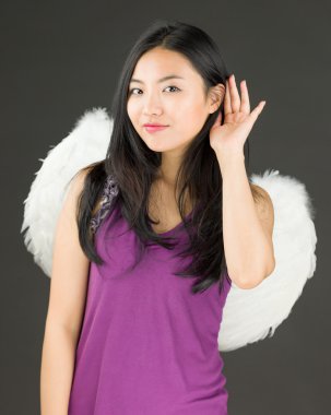 Dikkatle dinlemek çalışan bir melek Asyalı genç kadın giyinmiş