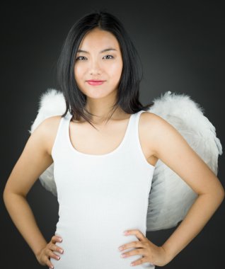 Kolları akimbo ile melek gibi giyinmiş kendine güvenen Asyalı genç kadın.