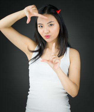 Asyalı genç kadın şeytan boynuzlarını ve parmak ile yapım çerçeve