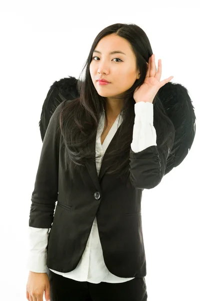 Asian young businesswoman dressed up as black angel hand to ear listening isolated over white background — Stock Photo, Image