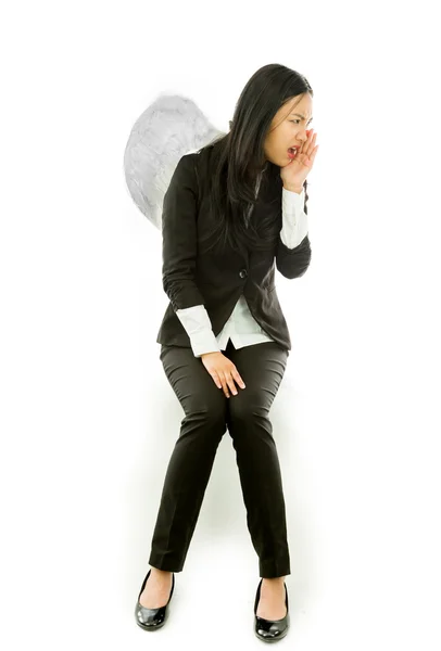 Angry Asian young businesswoman sitting on stool dressed up as an angel whispering message isolated on white background — Stock Photo, Image