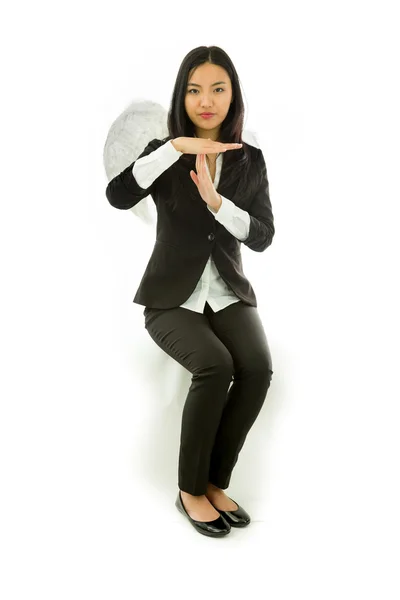Asiática joven mujer de negocios sentado en taburete vestido como un ángel mostrando señal de tiempo de espera aislado sobre fondo blanco —  Fotos de Stock