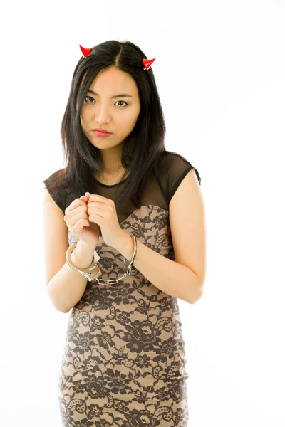 Upset Asian young woman dressed up as a devil with handcuffs isolated on white background — Stock fotografie