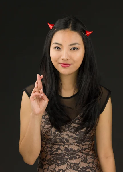 Asiático jovem mulher vestida como um diabo mostrando seus dedos cruzados — Fotografia de Stock