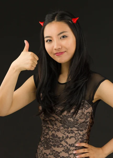Asiático jovem mulher vestida como um diabo com mostrando polegar para cima sinal — Fotografia de Stock