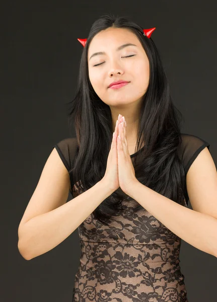 Asiático jovem mulher vestida como um diabo em posição de oração — Fotografia de Stock