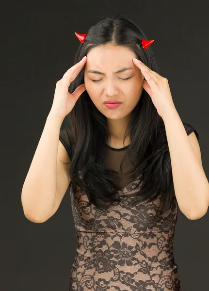 Asiática joven mujer vestida como un diablo que sufre de dolor de cabeza — Foto de Stock