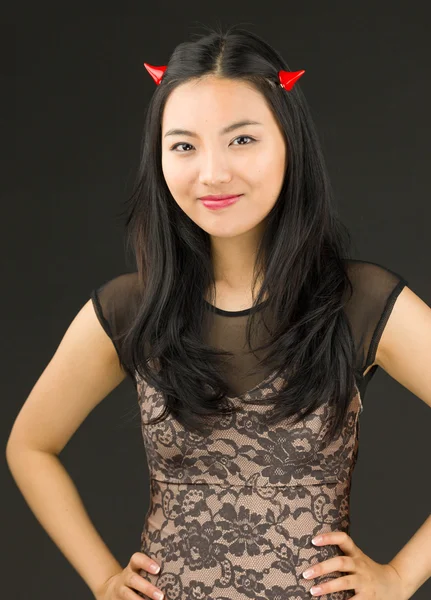 Asiatiska ung kvinna utklädd till en djävul står med armarna akimbo — Stockfoto