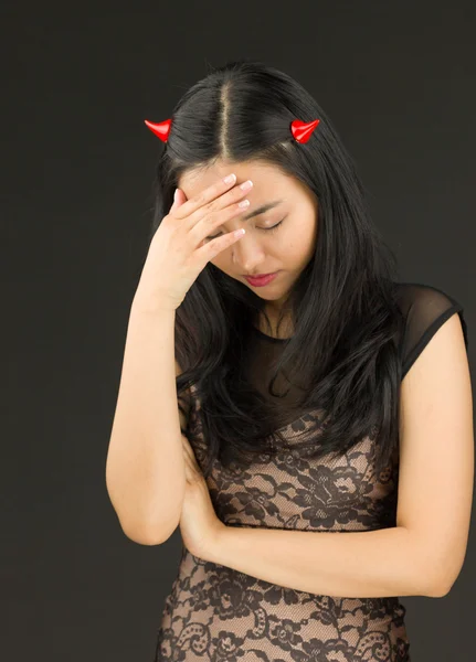 Perturbado ásia jovem mulher vestido até como um diabo com ela cabeça no mãos — Fotografia de Stock