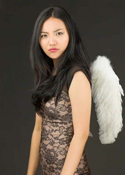 Melek gibi giyinmiş ciddi bir Asyalı genç kadın.