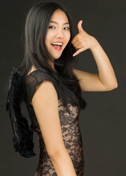 Asian young woman dressed up as a black angel pretending to calling — Stock Photo, Image