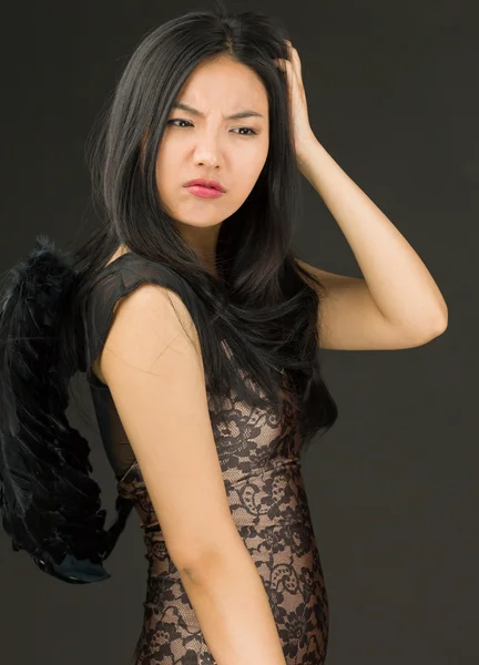 Azjatyckie młode kobiety ubrane jak czarny anioł zarysowania głowę — Zdjęcie stockowe