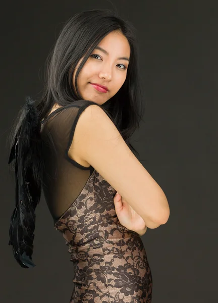 Side profile of a Asian young woman dressed up as a black angel with her arms crossed — Stock Photo, Image