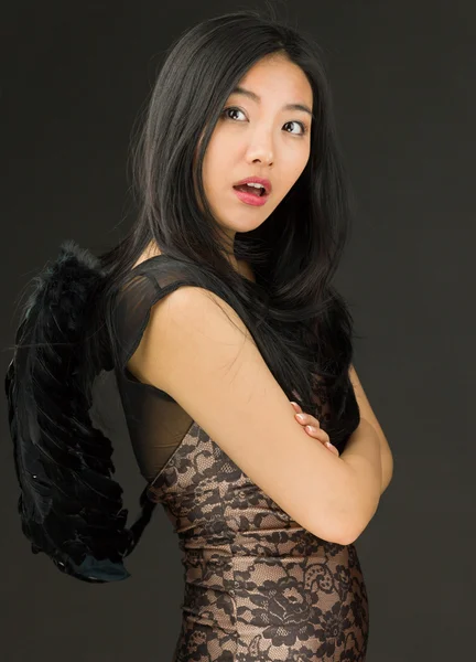 Side profile of a Asian young woman dressed up as a black angel with her arms crossed — Stock Photo, Image