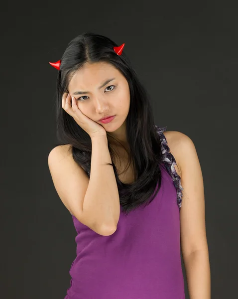 Côté diable d'une jeune femme asiatique avec ses mains sur la joue et l'air triste — Photo