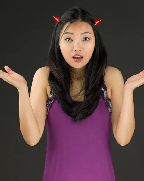 Lado diabólico de una joven asiática encogiéndose de hombros y mirando confundida —  Fotos de Stock
