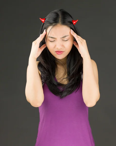 Lado diabólico de una joven asiática que sufre de dolor de cabeza — Foto de Stock