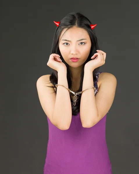 Devil side of a young Asian woman with handcuffs and looking sad — Stock Photo, Image