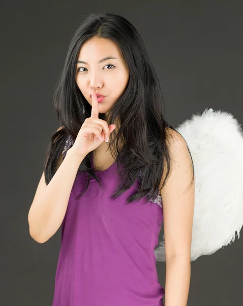 Angel side of a young Asian woman standing with finger on lips asking for silence — Stock Photo, Image