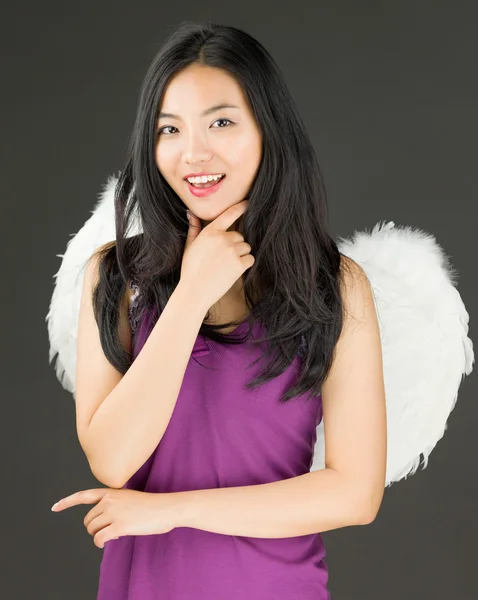 Angel side of a young Asian woman standing with hand on chin and smiling — Stock Photo, Image