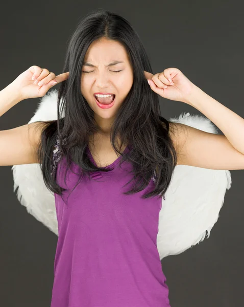 Angel side of a young Asian woman shouting in frustration with fingers in ears — Stock Photo, Image