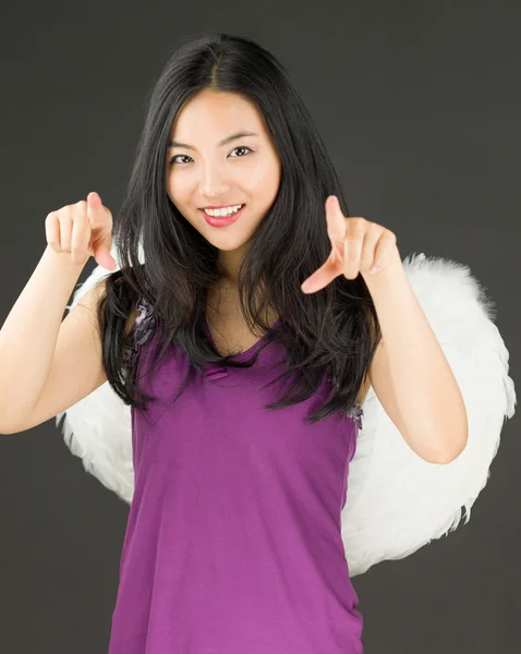 Ангельская сторона молодой азиатки, указывающей обеими руками и улыбающейся — стоковое фото