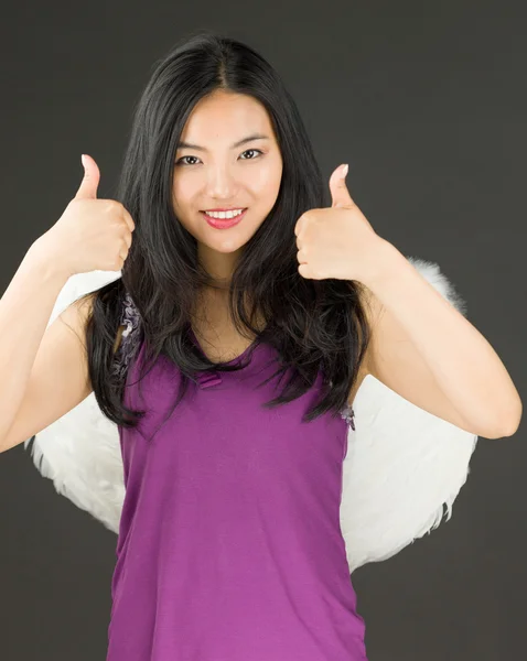 Côté ange d'une jeune femme asiatique montrant pouces vers le haut signe avec les deux mains et souriant — Photo