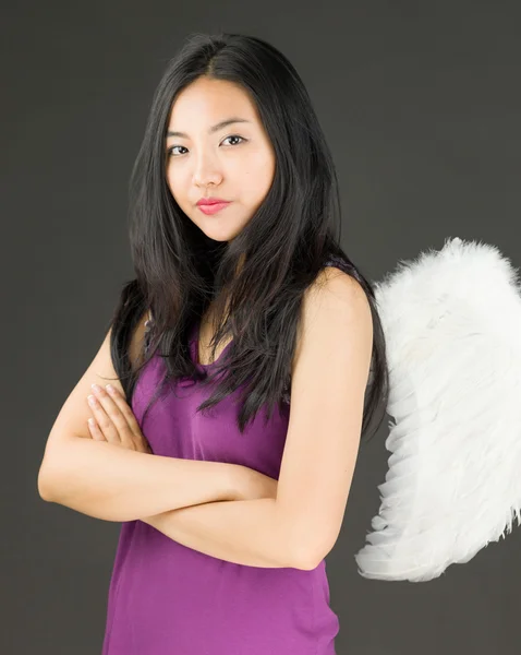 Côté ange d'une jeune femme asiatique debout avec les bras croisés et l'air confiant — Photo