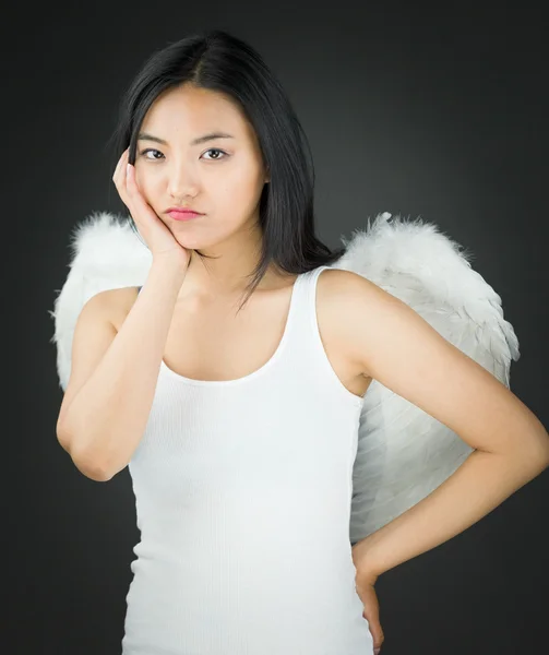 Upset Asian young woman dressed up as an angel with her hands on cheek and hand on hip — Stock Photo, Image