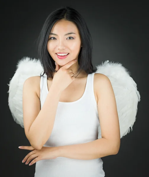 Asiático jovem mulher vestida como um anjo com a mão no queixo e sorrindo — Fotografia de Stock