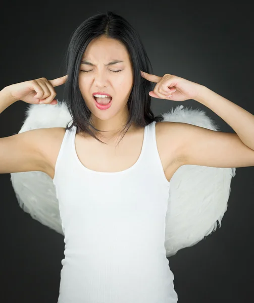 Frustrerad asiatiska ung kvinna utklädd som en ängel med fingrarna i öronen — Stockfoto