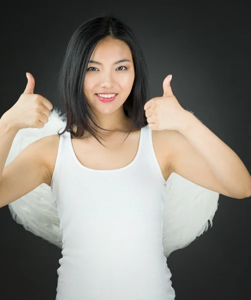 Ásia jovem mulher vestido até como um anjo mostrando polegar para cima sinal com ambos mãos — Fotografia de Stock