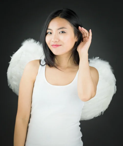 Asijské mladá žena, oblečená jako anděl snaží naslouchat pozorně — Stock fotografie