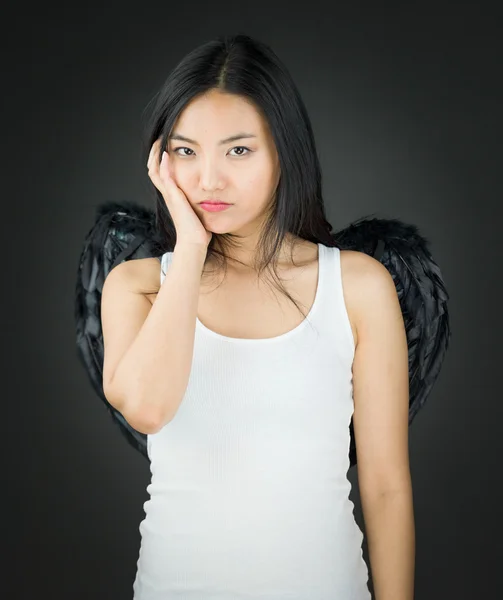 Zdenerwowany azjatyckich młodej kobiety ubrane jak anioł z jej ręce na policzku — Zdjęcie stockowe
