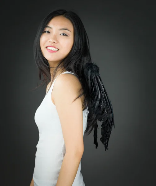 Vista laterale di una giovane donna asiatica vestita da angelo sorridente — Foto Stock