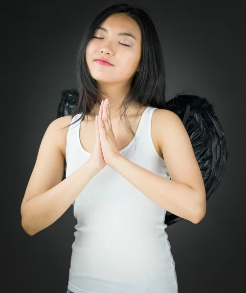 Aziatische jonge vrouw verkleed als een engel in gebed standpunt met handen geklemd — Stockfoto