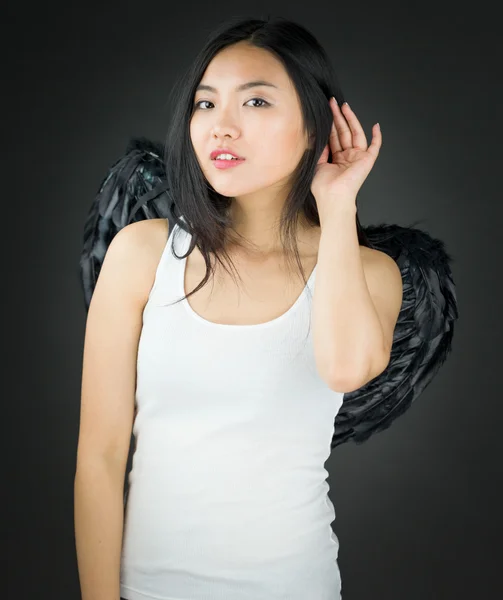 Asiatiska ung kvinna utklädd till en ängel försöker lyssna noga — Stockfoto