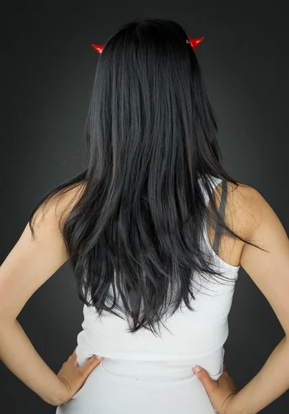 Vista posteriore di una giovane donna asiatica in corna di diavolo con le braccia akimbo — Foto Stock