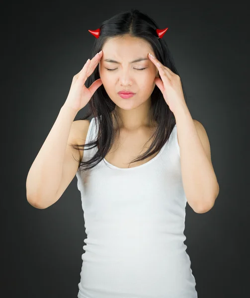 Stressad asiatisk ung kvinna i djävulen horn lider av huvudvärk — Stockfoto