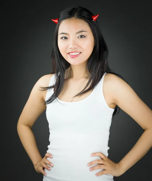 Asian young woman in devil horns pretending with her arms akimbo — Stock Photo, Image