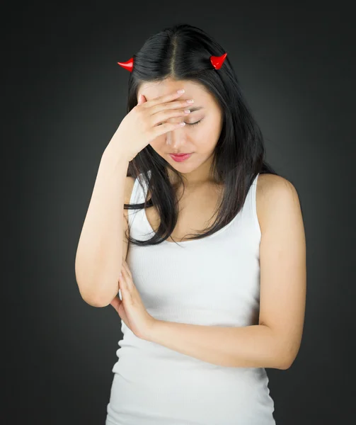 Upset Asian young woman in devil horns her head in hands — Stock Photo, Image