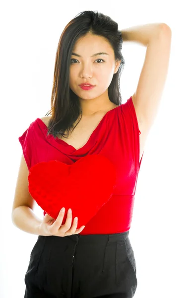 Young woman standing with heart shape cushion — Stock Photo, Image