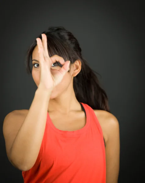 Porträtt av en ung kvinna som ser genom fingrarna hål — Stockfoto